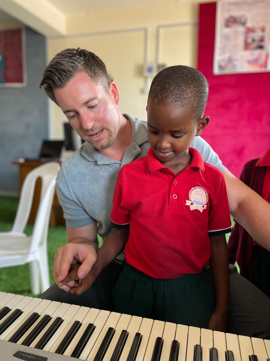Marcel Maciej shows a young student where to place his fingers on the keyboard