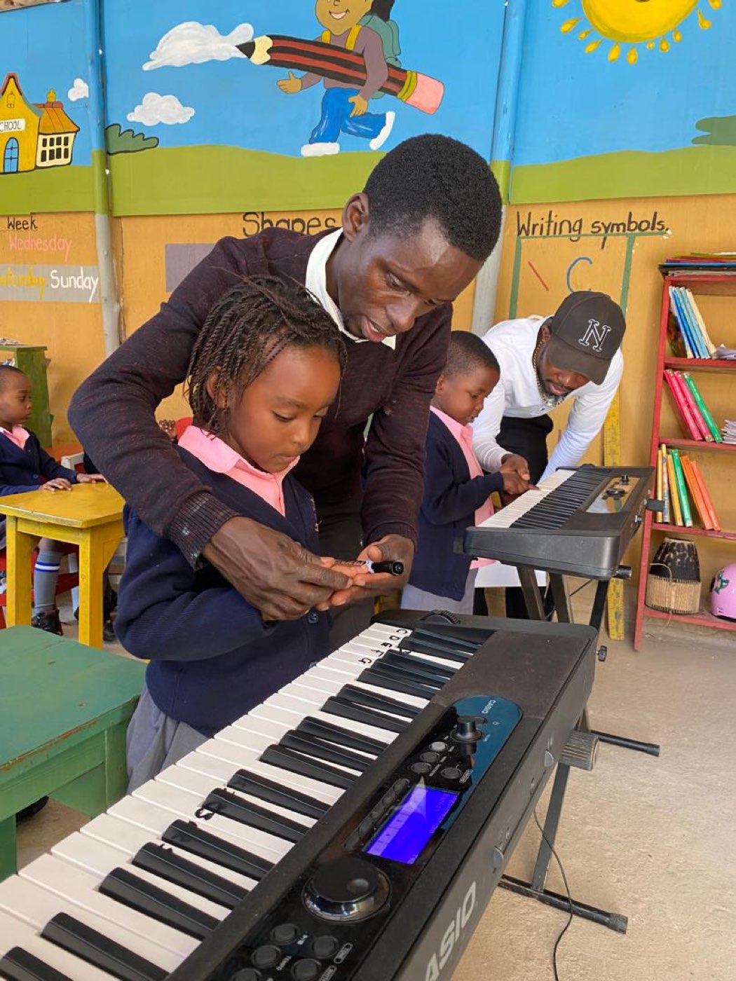 A teacher guides a little girl's hands on the keyboard